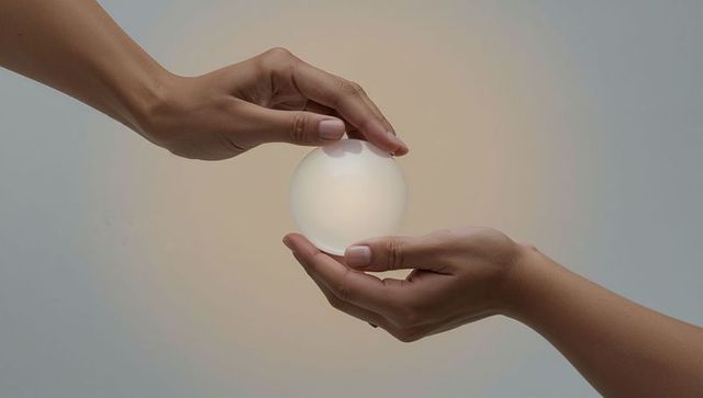 Hands cradling glowing orb emitting soft warm light for wellness concepts