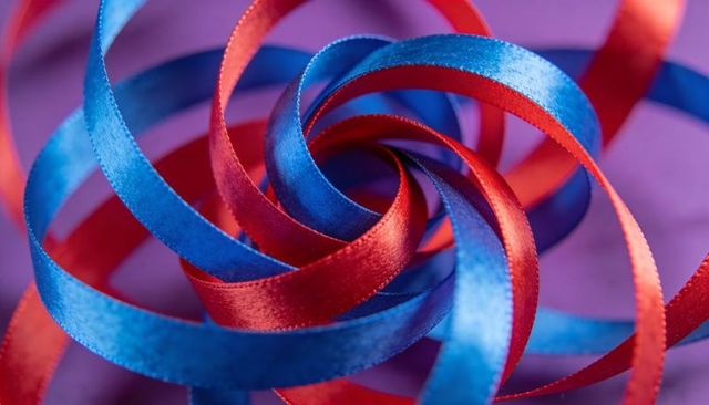 Twisted red and blue satin ribbons spiral macro purple background
