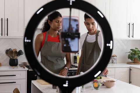 African american couple cooking and recording tutorial with ring light in modern kitchen