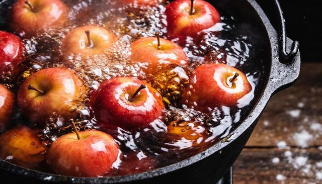 Bubbling cast iron pot simmering red apples in glossy syrup for rustic fall dessert