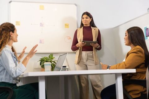 Leading team meeting with tablet and whiteboard in modern office for marketing strategy