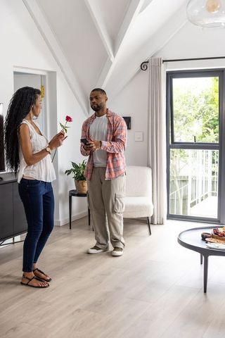 Couple exchanging red rose in modern living room during tender romantic moment