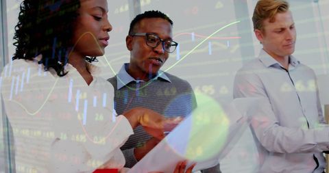 Team Analyzing Financial Data with Graphs Overlay in Modern Office