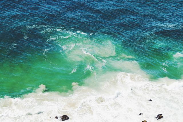 Image presents aerial view of waves crashing into a beach with stunning turquoise water. Suitable for travel, nature, and beach promotions, adding vibrant and serene atmosphere to blogs, articles, and marketing materials.