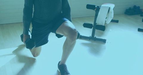 Man performing weighted lunge in home gym environment