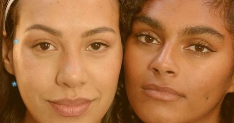 Warm closeup headshot featuring two women with glowing skin and headband, beauty portrait