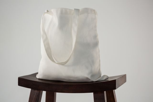 White bag on wooden stool against white background