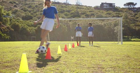 Female Soccer Players Training with Cones on Sunny Field