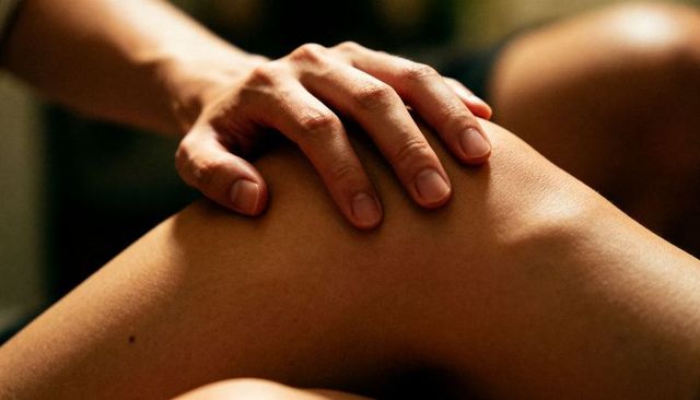 Resting adult woman hand pressing bare thigh closeup, neat nails and skin texture
