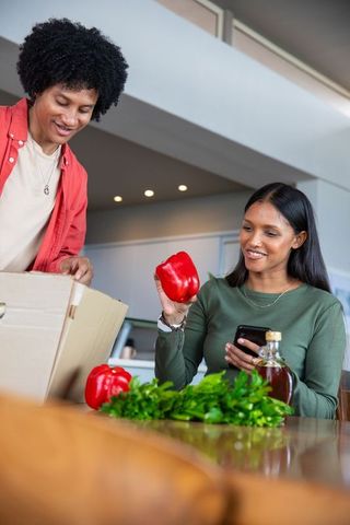 Couple unpacking fresh groceries at modern kitchen table