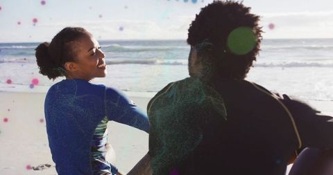 Couple in Wetsuits Enjoying Beach View on Sunny Day