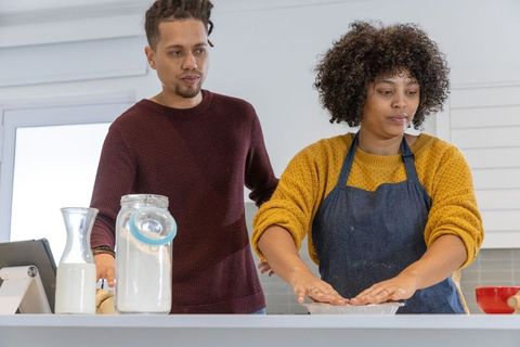 African american couple baking together in modern kitchen, woman pressing dough into pan