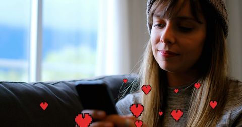 Woman texting on couch with digital hearts overlay