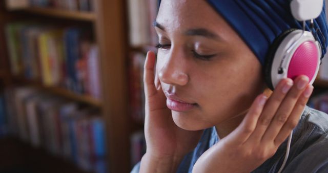 Young Woman with Headscarf Listening to Music with Headphones in Library - Download Free Stock Images Pikwizard.com