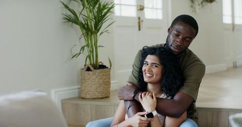 Couple embracing in sunlit entryway sharing cozy warmth and affectionate hug
