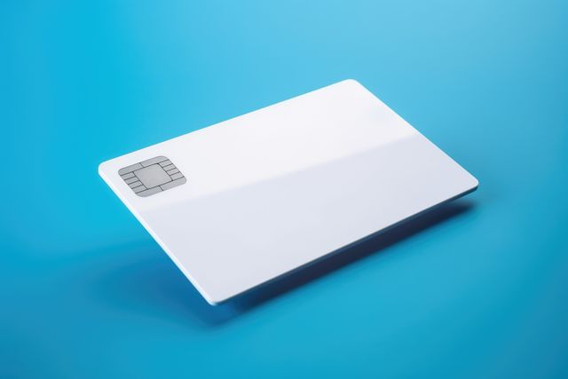 Blank white credit card with microchip on blue, copy space, created using generative ai technology. Emv chip, banking, spending, technology and finance mock up concept digitally generated image.