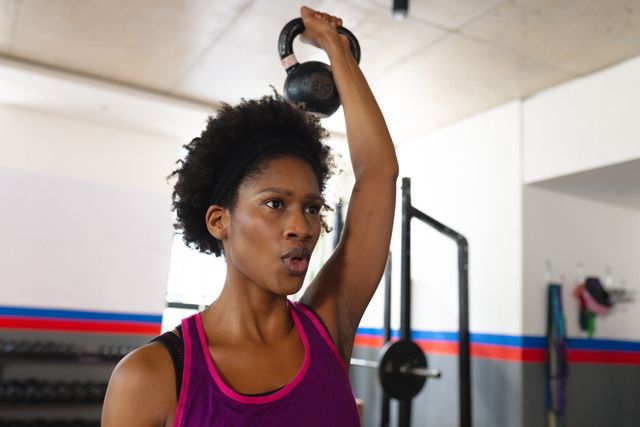 Photo of african american fit woman exercising in gym with wieghts. Fitness, health, active lifestyle and sport concept.