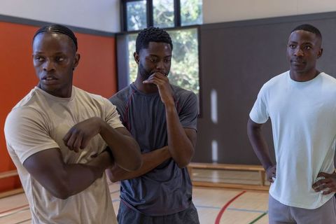 African american athletes discussing training plan on indoor gym court during practice