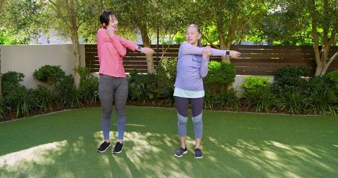 Mother and daughter stretching and exercising outdoors for wellness