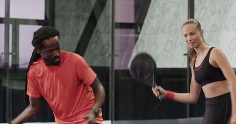 Woman practicing padel tennis with coach in modern indoor court