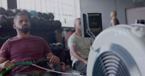 Men Training on Rowing Machines with Data Overlay at Gym