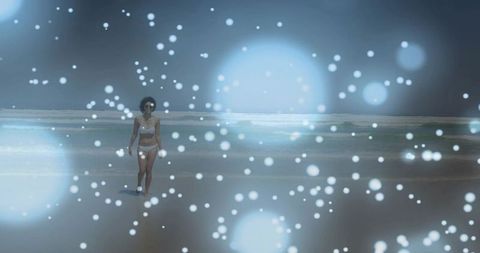 Woman walking on misty shoreline in white bikini wearing sunglasses with dreamy bokeh