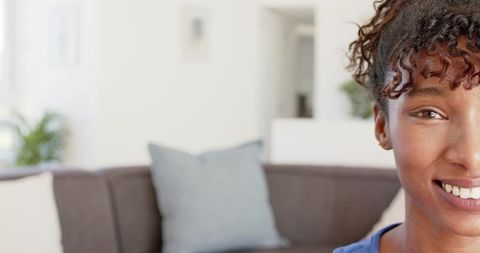 Bright close-up half portrait of african american woman smiling in modern living room