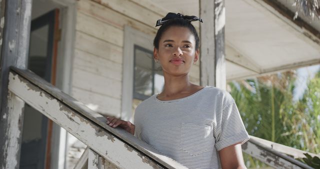 Happy biracial woman standing on stairs of house on beach. Lifestyle, nature, relaxation, vacation, summer and leisure, unaltered.