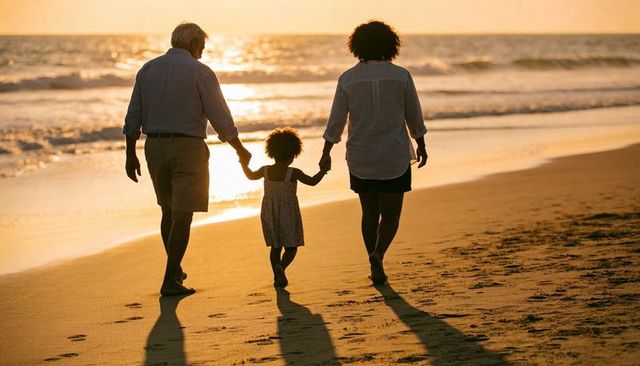 Golden hour family walking on beach holding hands along sunlit shoreline at sunset
