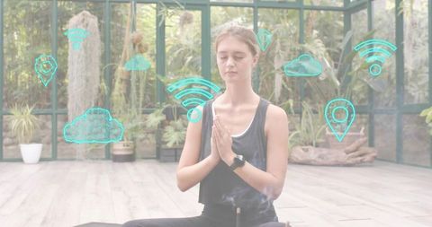 Young woman meditating in greenhouse surrounded by holographic connectivity icons and incense