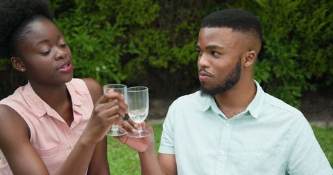 Young Couple Toasting with Drinks and Enjoying Each Other's Company Outdoors