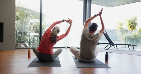 Senior Couple Doing Yoga Stretching at Home with Smartwatches