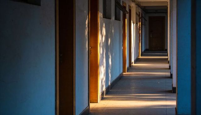 Sunlit minimalist corridor with wooden doors, strong perspective and golden hour shadows