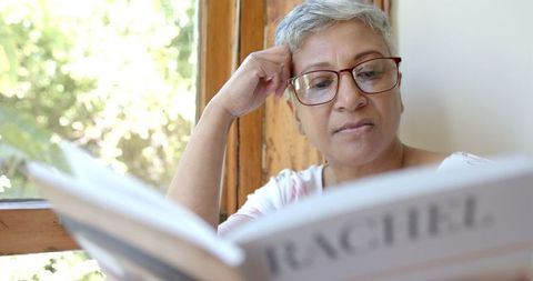 Relaxed Senior Woman Enjoying Literature by Window Light