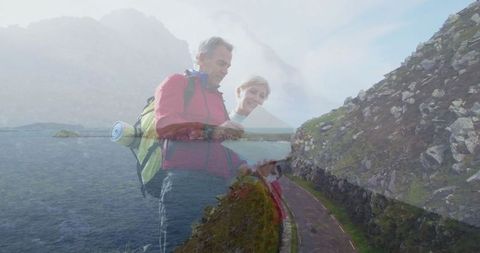 Couple hiking coastal trail studying map on rugged path
