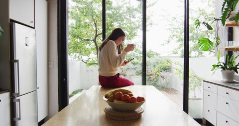 Transgender Woman Enjoying Relaxation by Kitchen Window with Coffee - Download Free Stock Images Pikwizard.com