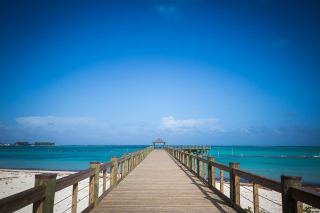 Scene features a wooden pier stretching into a turquoise ocean under a clear blue sky. Useful for travel brochures, vacation advertisements, relaxation-themed content, and websites about tropical destinations.