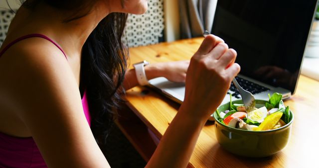 Woman using laptop while having breakfast at home