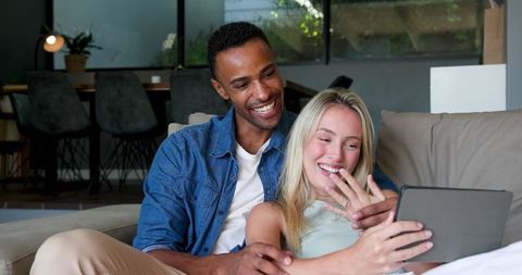 Excited Couple Sharing Engagement News on Tablet at Home