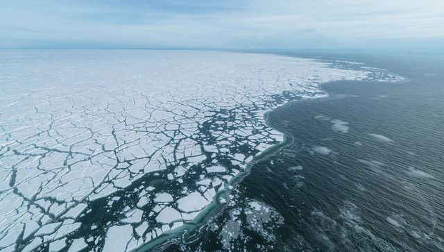 Cracked arctic sea ice breaking into polygonal floes revealing open-ocean channel aerial