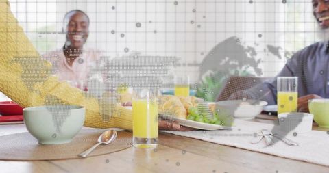Multigenerational Family Reaching for Breakfast Plate During Morning Meal With Global Map Overlay