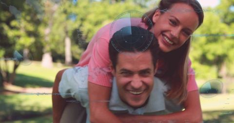 Playful couple piggybacking in sunny park with futuristic hud overlay