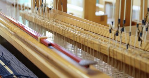 Close-up of threaded hand loom in solar-powered workshop