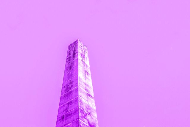 Abstract representation of a tall monument set against a vibrant purple sky. Perfect for use in modern art projects, as a visual background for advertising, or in creative design portfolios to convey modernity and uniqueness.