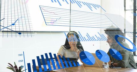Colleagues analyzing blue data visuals on laptops during collaborative office meeting