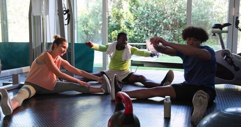 Diverse Friends Stretching Together in Modern Gym
