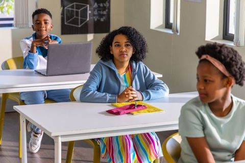 African American Students Sitting in Classroom Focusing on Learning with Laptop and Notebooks