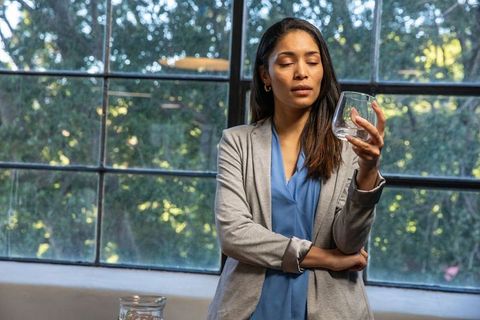 Contemplative Woman Holding Stemless Glass by Window Amidst Elegant Interior