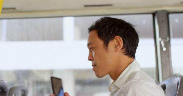 Asian man checks his phone on a bus, with copy space - Download Free Stock Photos Pikwizard.com
