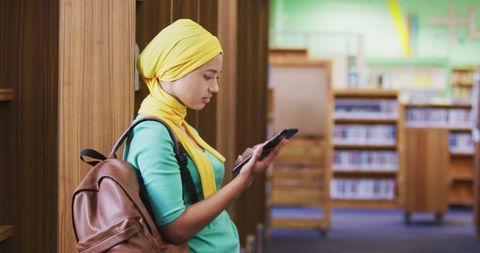 Teen Student Using Smartphone in Library Environment
